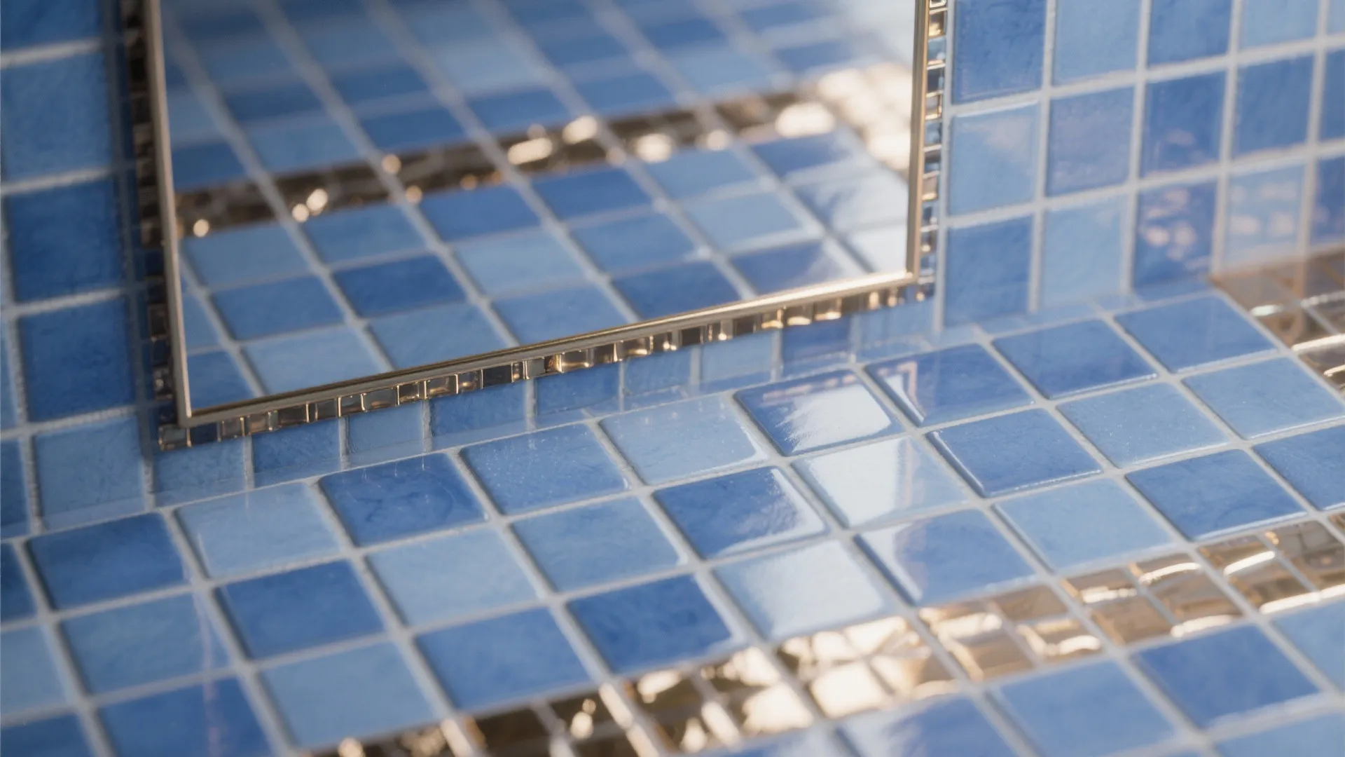 Close up of small blue wall tiles showing shiny surfaces and reflection in bathroom mirror