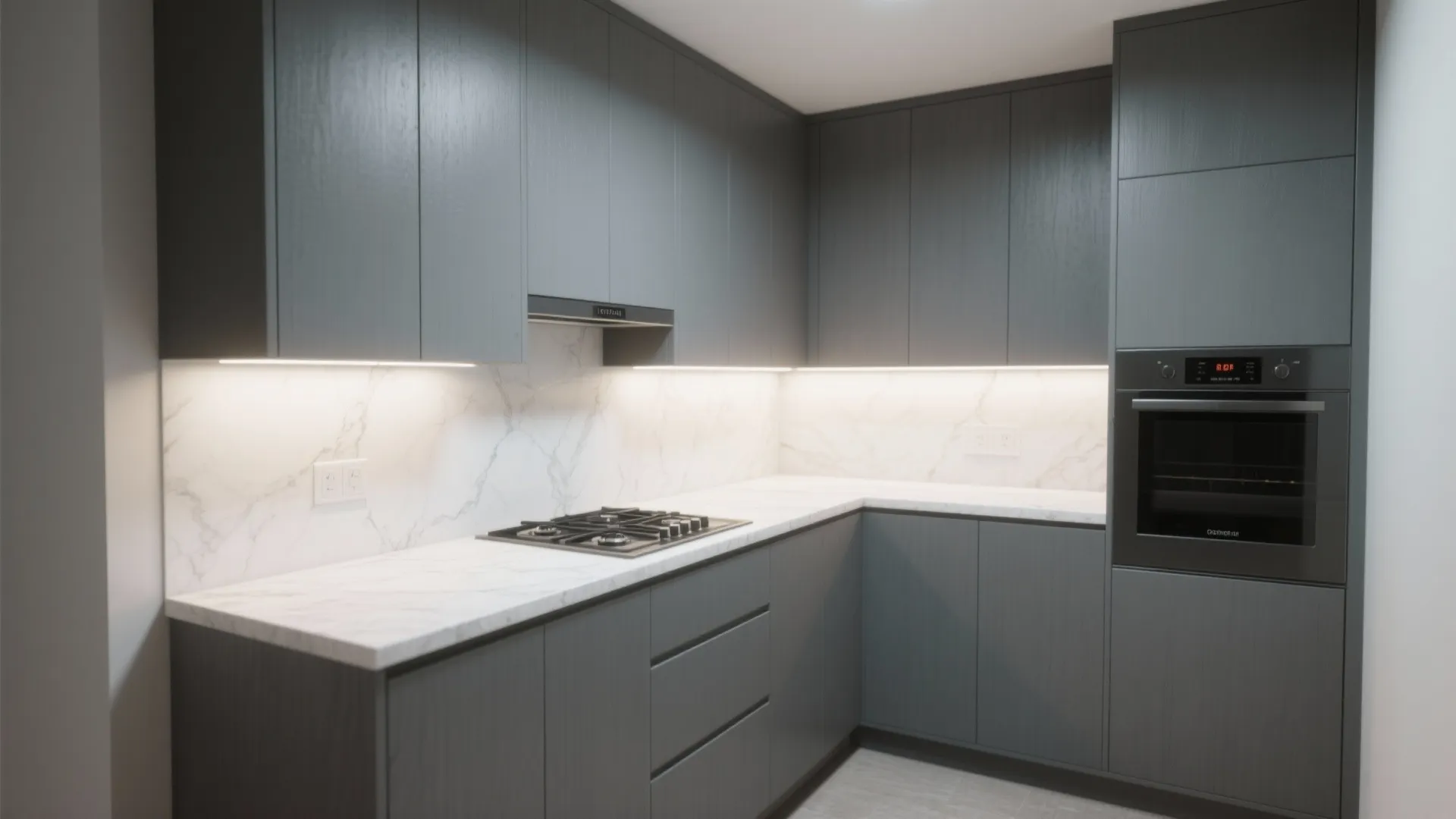 Modern kitchen with dark grey cabinets white marble backsplash integrated oven and warm under cabinet lighting
