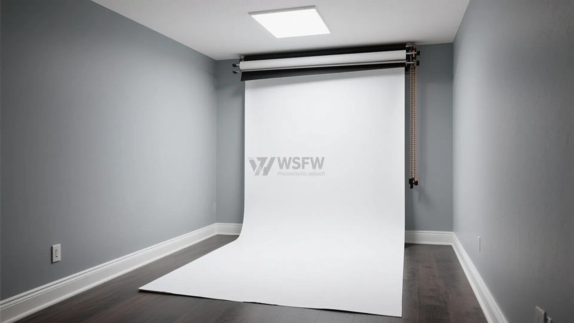 Photo studio room with gray walls dark wood floor and a white paper background roll