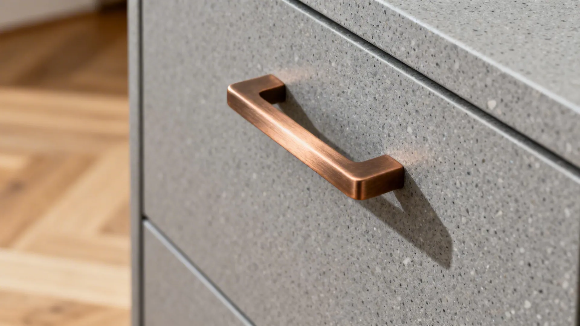 Macro of matte gray acrylic cabinet with warm brushed metal pull.