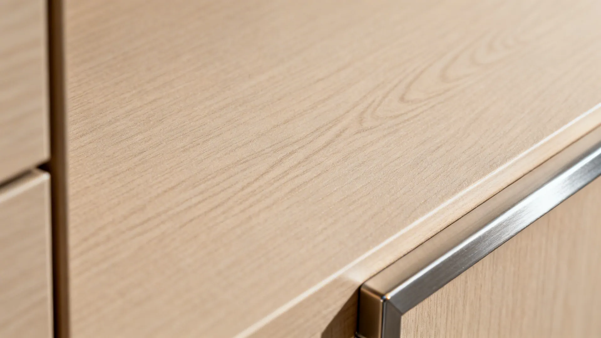 Close up of light wood texture cabinet surface with a silver metal handle and natural grain