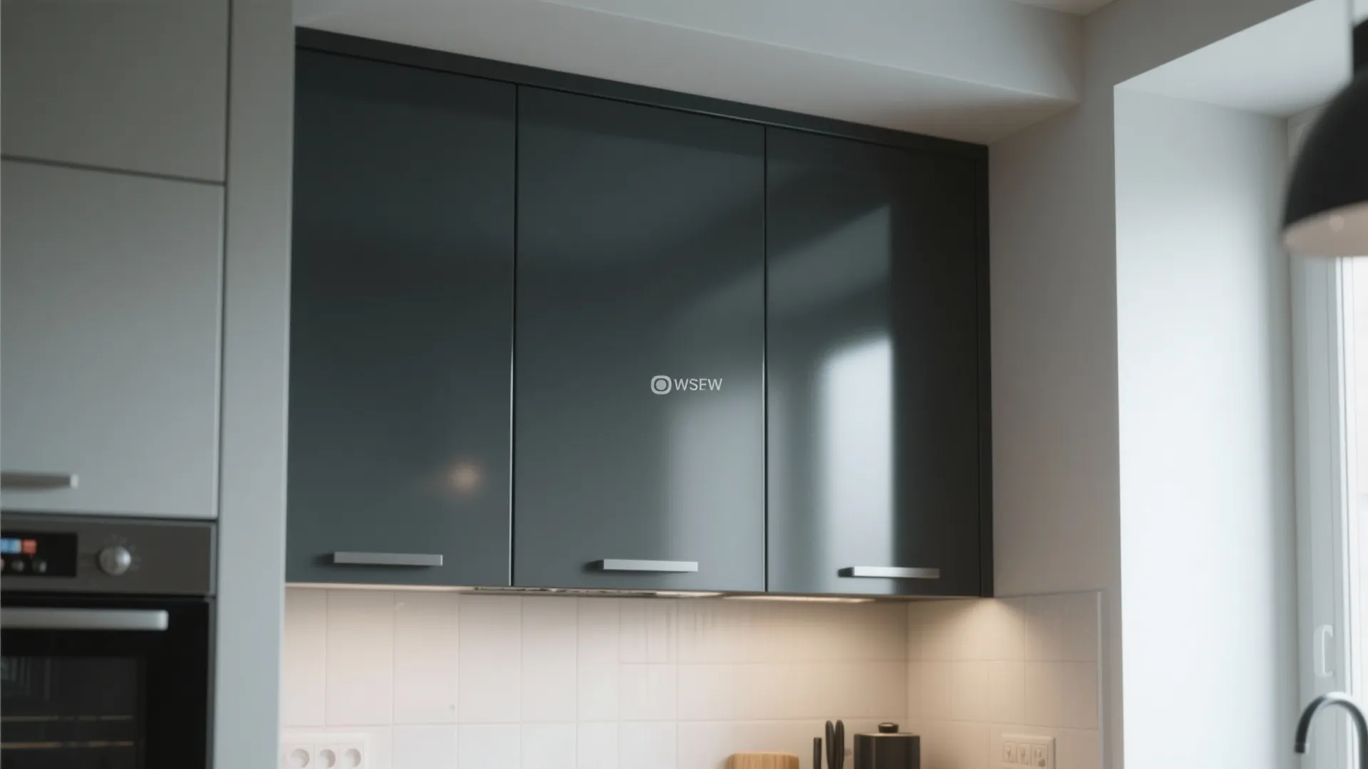 Close-up of dark grey kitchen cabinet doors with white tile backsplash and warm cabinet light