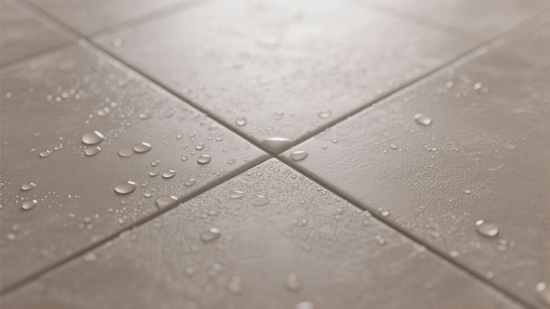 Close up view of wet grey floor tiles with water droplets and soft indoor natural light