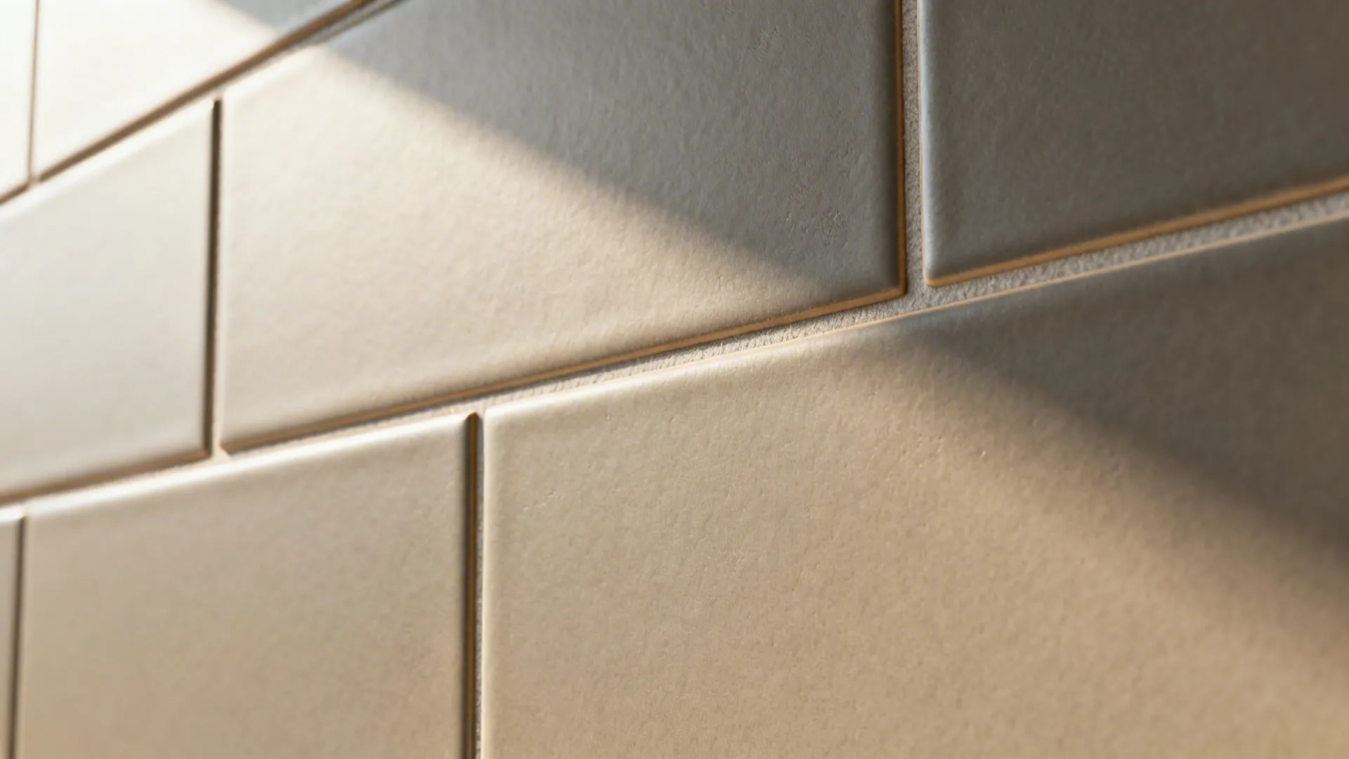 Macro of warm gray matte porcelain subway tiles with tight grout for a calm backsplash.