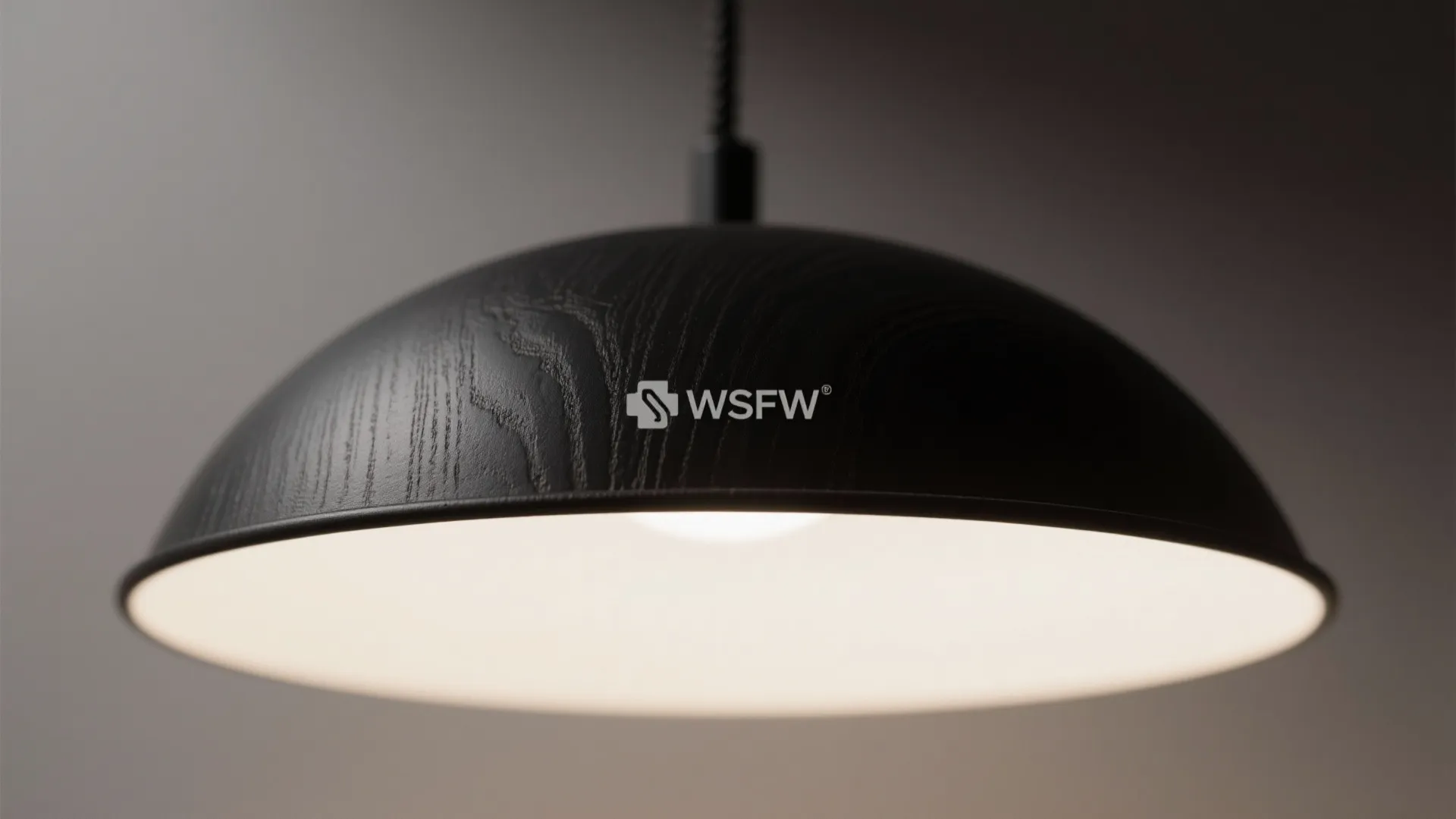 Close up of a black dome shaped ceiling light with wood texture and warm interior glow