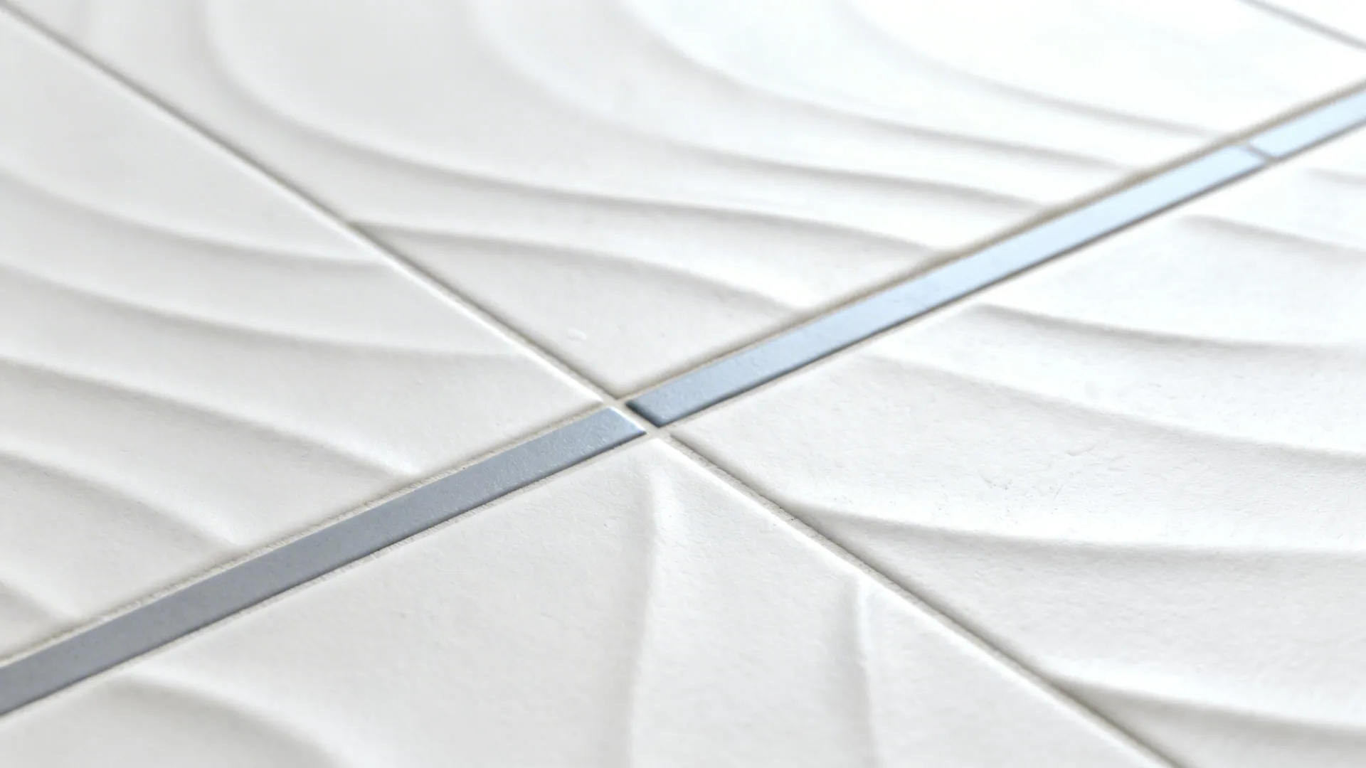 Macro detail of matte white hand-pressed tile with a slim cool grey accent strip.