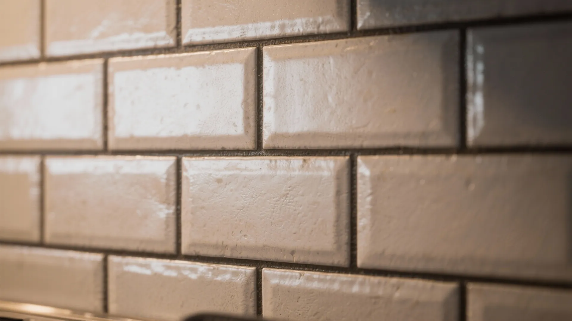 Close-up of matte textured subway tiles with dark grout in an offset pattern.