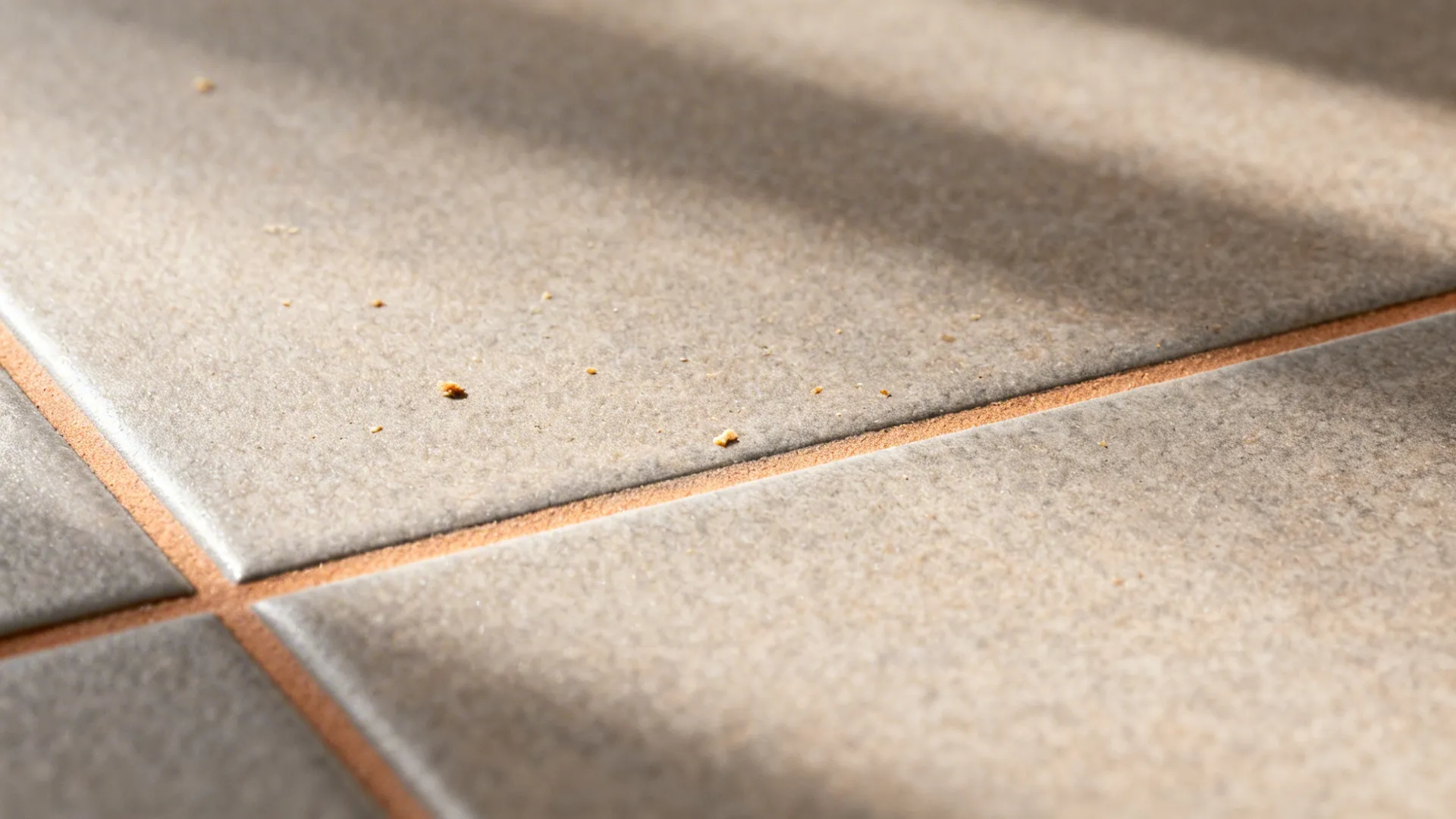 Macro view of warm grey matte porcelain tile with subtle texture and matching grout.