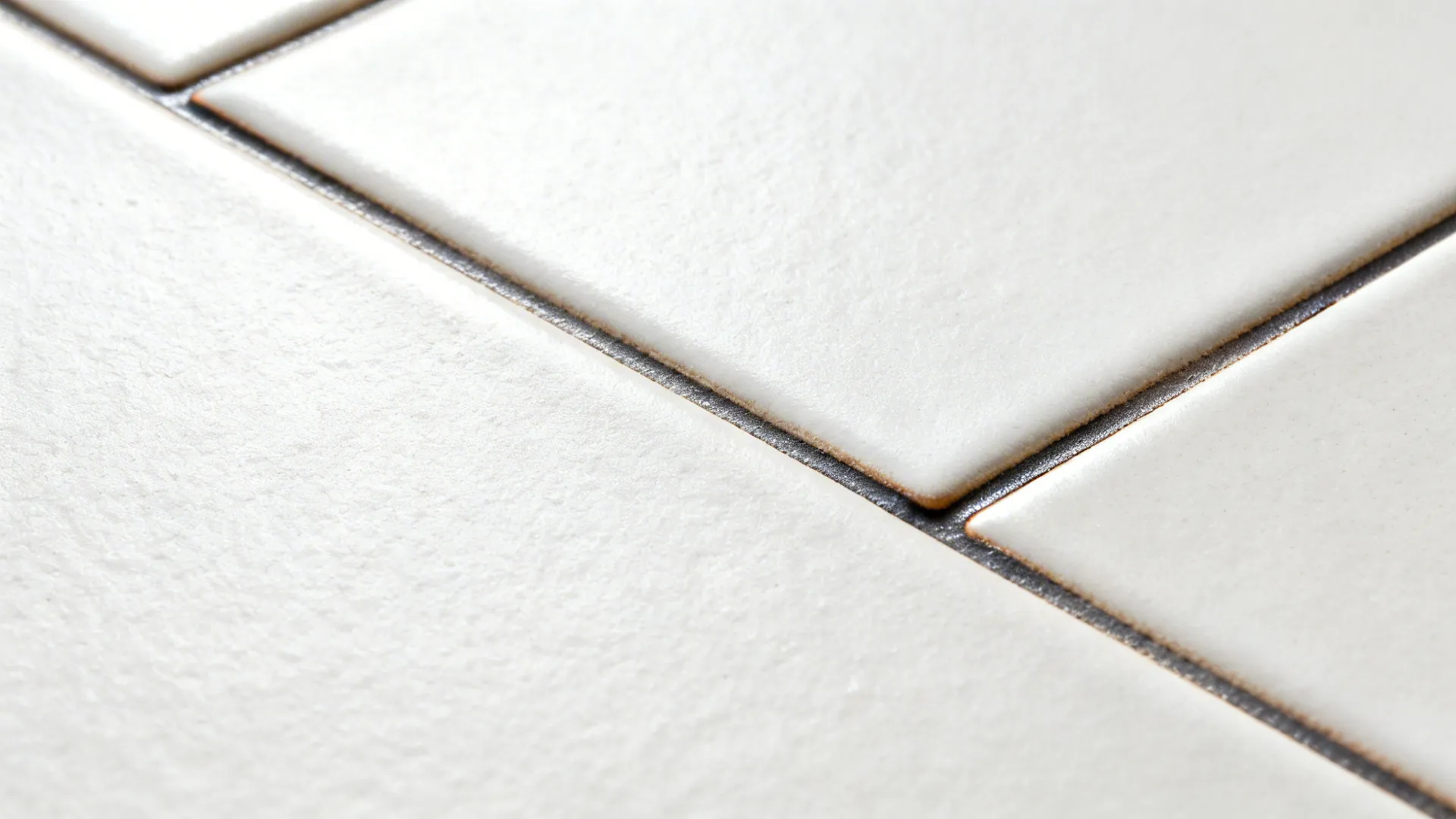 Macro of matte ceramic subway tile with dark epoxy grout showing low-sheen texture under soft daylight.