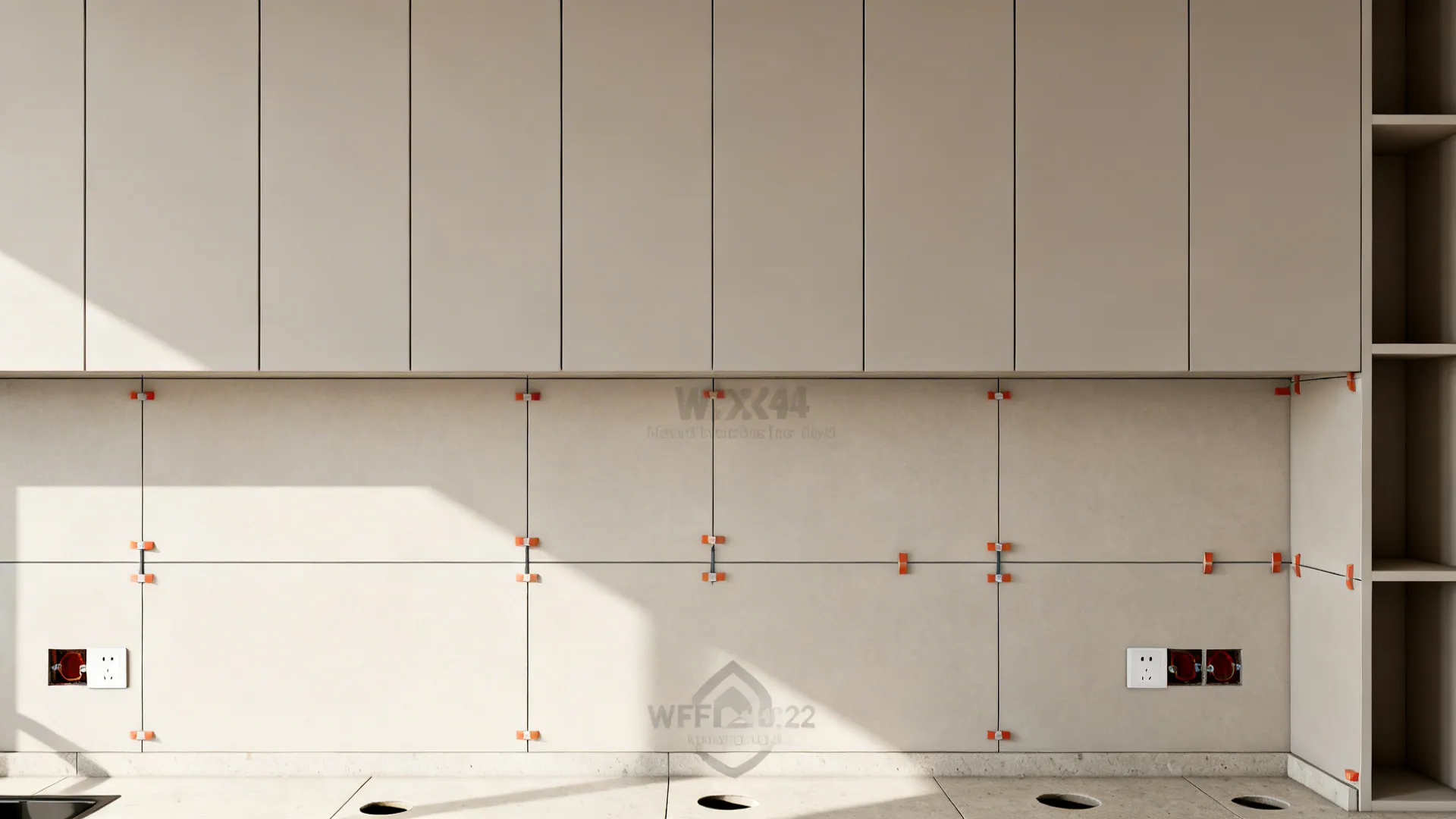 Cream wall tiles being installed with orange leveling clips under light colored kitchen cabinets and storage