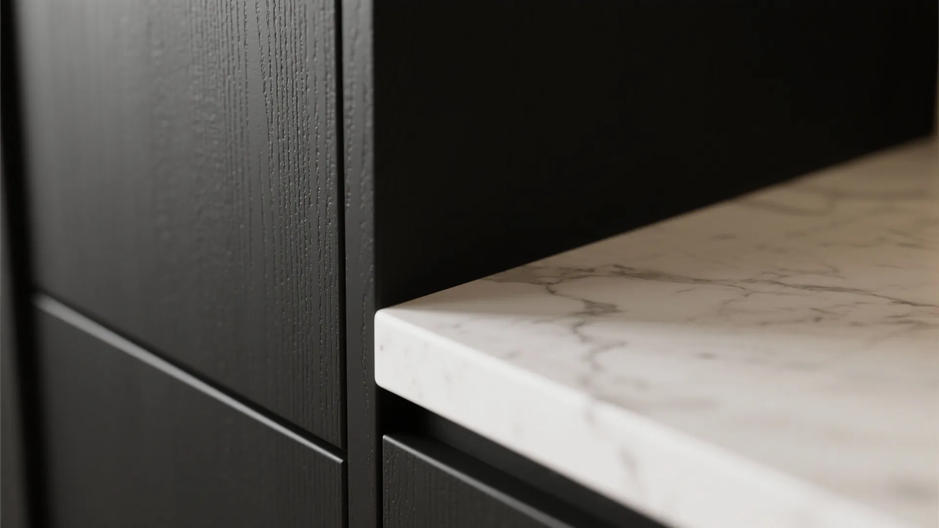Close up view of black wood wall panel meeting a white marble kitchen island countertop