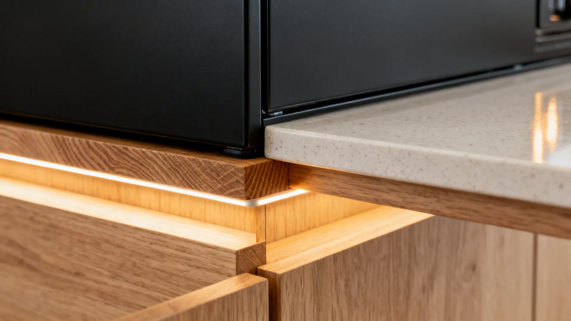 Close-up of matte black finish meeting light oak with warm LED glow on quartz.
