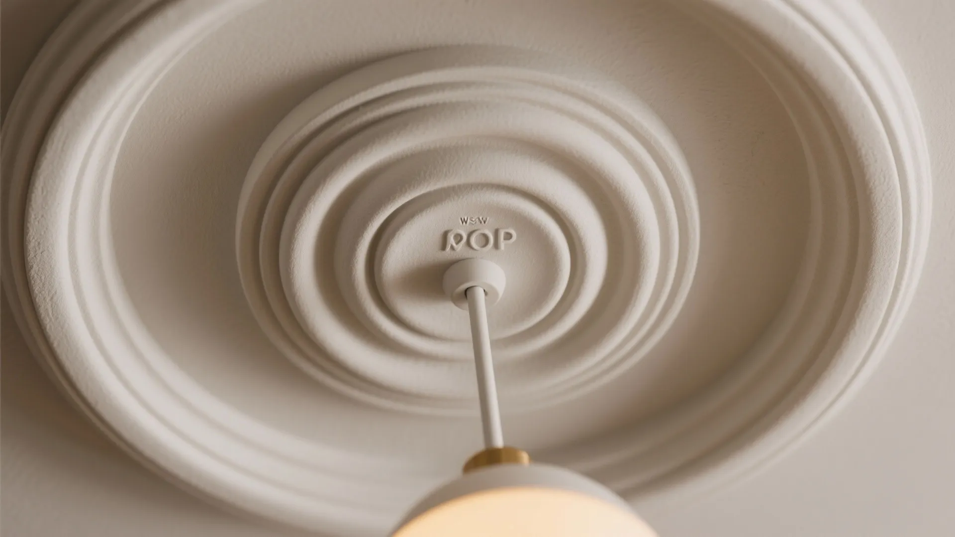 Close up of a round white ceiling decoration with a small hanging white ceiling light fixture
