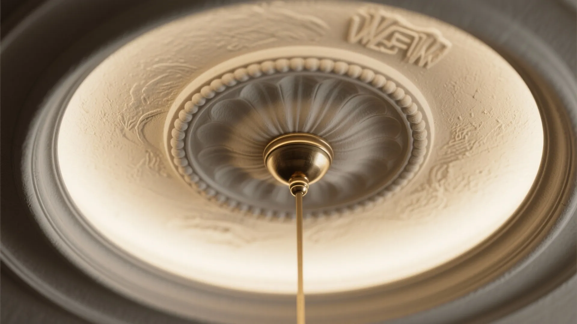 Close up view of decorative white ceiling light base with gold metal rod and warm light