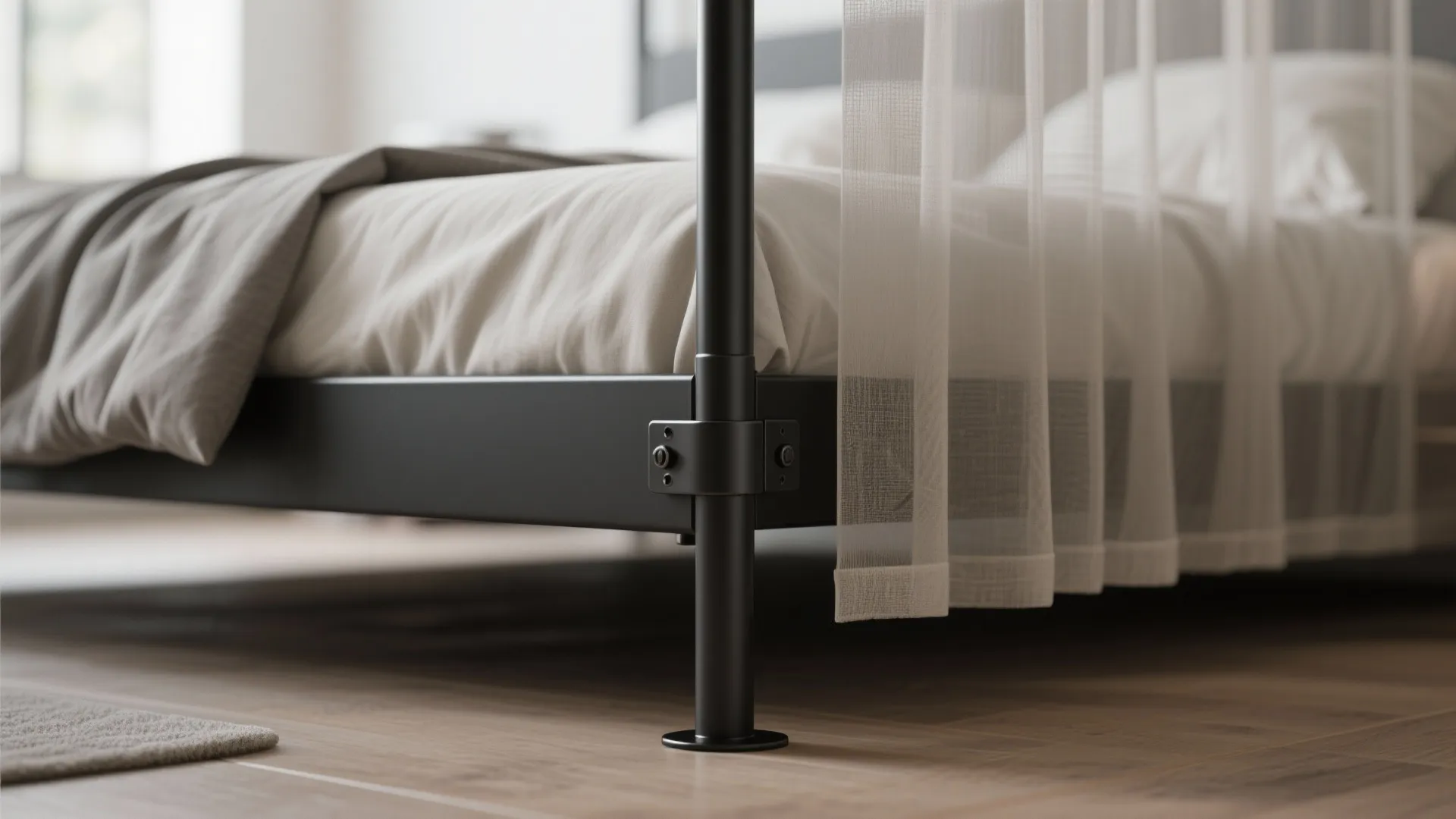Close up of black metal bed frame leg with white sheer curtain and wooden floor
