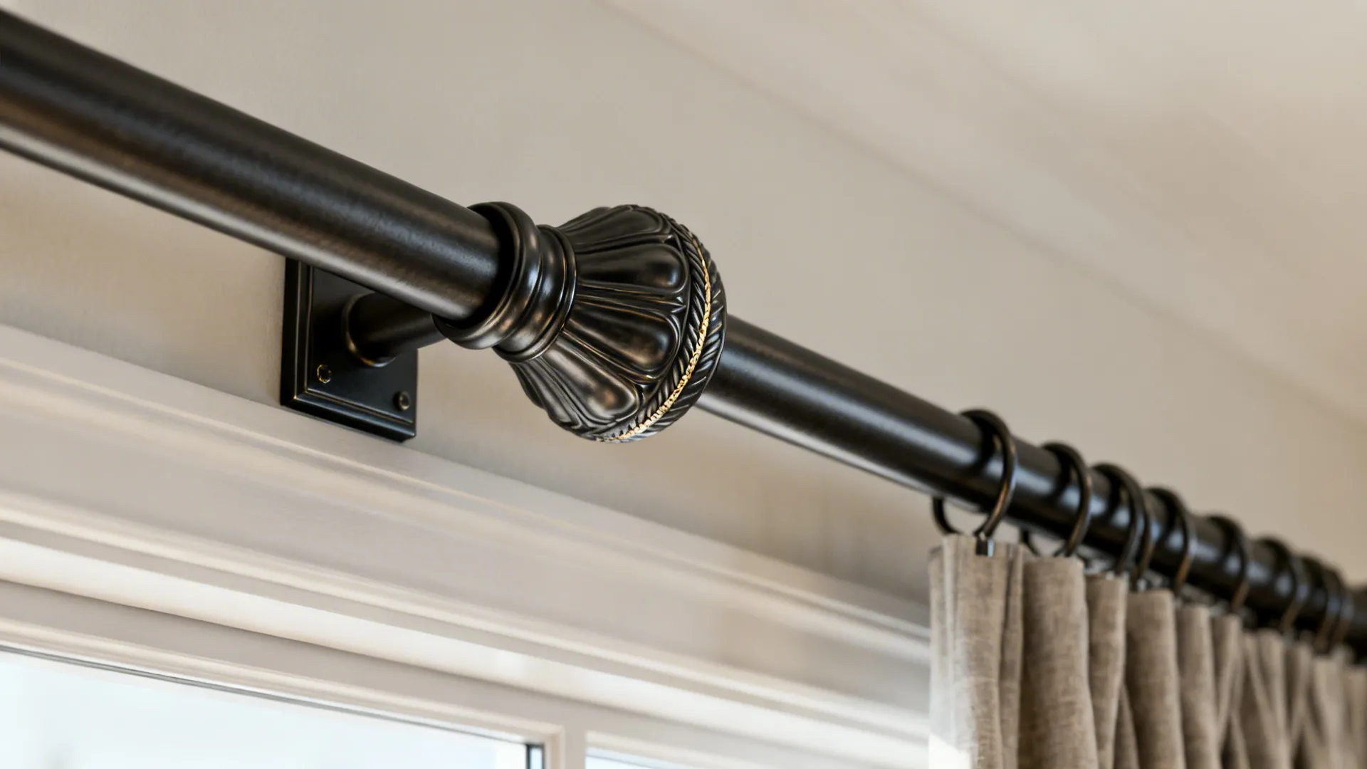 Close-up of a matte black metal curtain rod with decorative finial and wall bracket