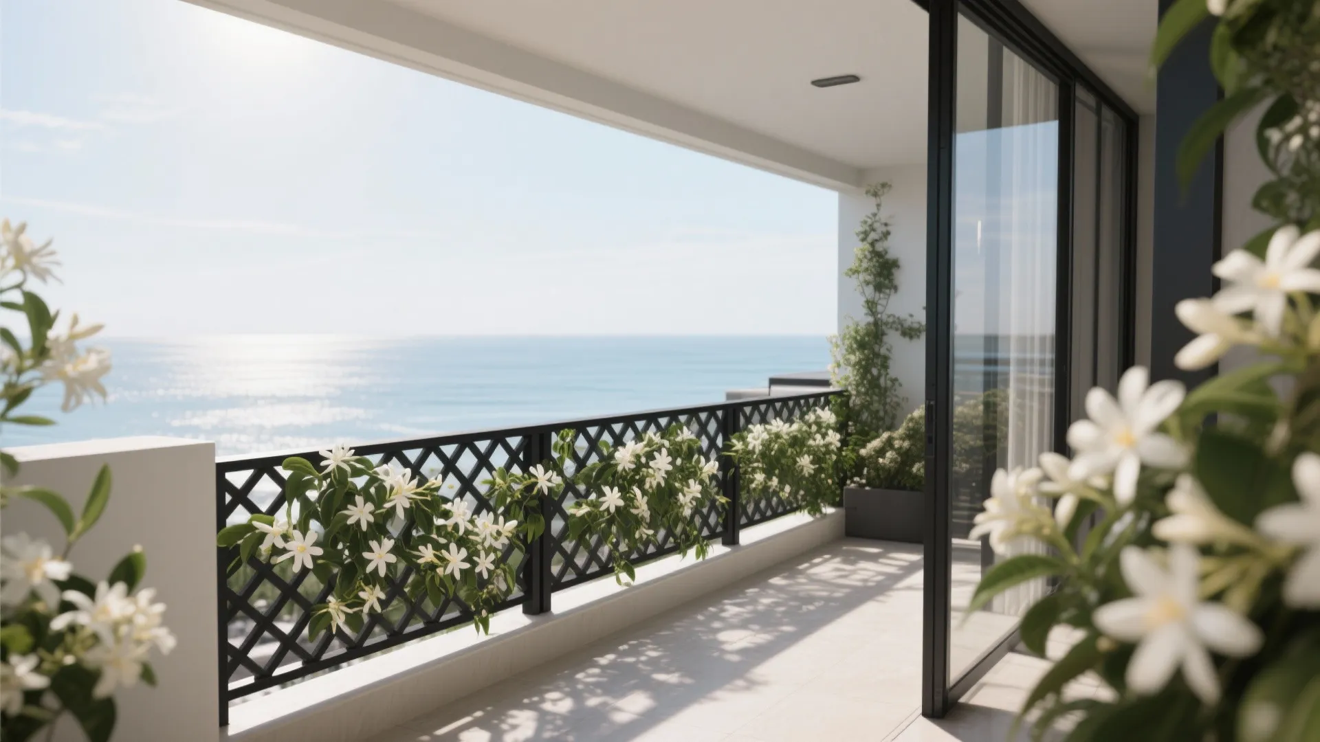 White flowers on black metal fence of a balcony overlooking blue ocean under clear sky