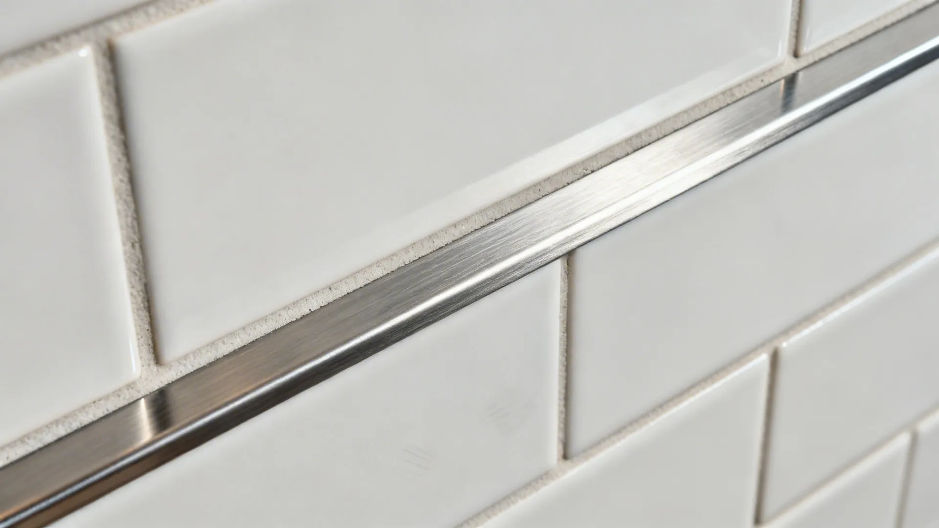 Close-up of brushed stainless accent tile with clean trim against white subway tile.