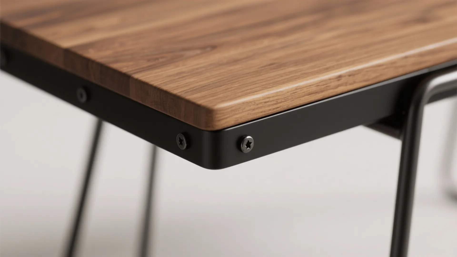 Close up of a wooden table top with black metal frame and screws for furniture
