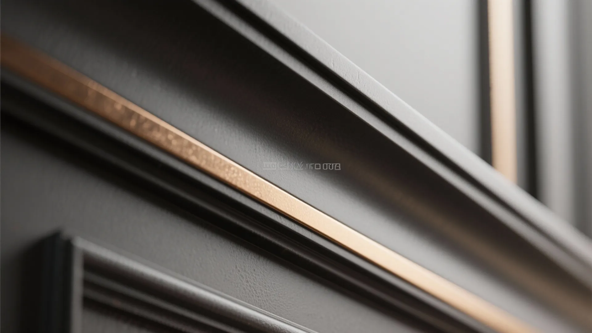Close-up of dark semi-gloss trim with a thin warm bronze metallic accent strip catching soft highlights.