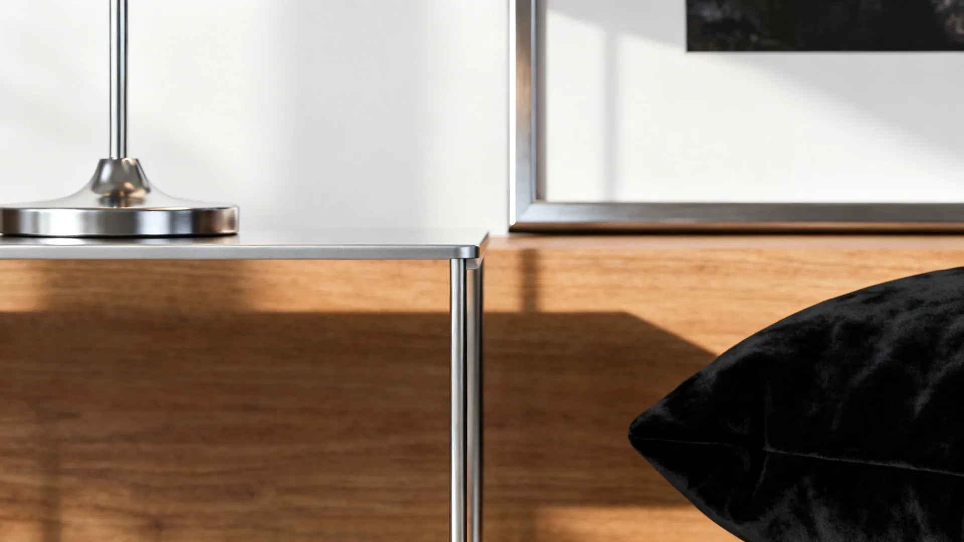 Close-up of silver lamp base and slim coffee table with velvet cushion and wood surface