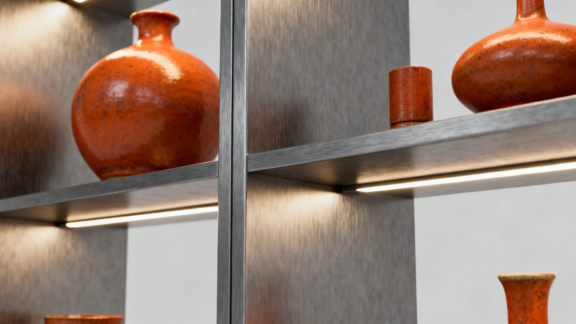 Modern gray metal wall shelf with light strips and several decorative orange round ceramic vases