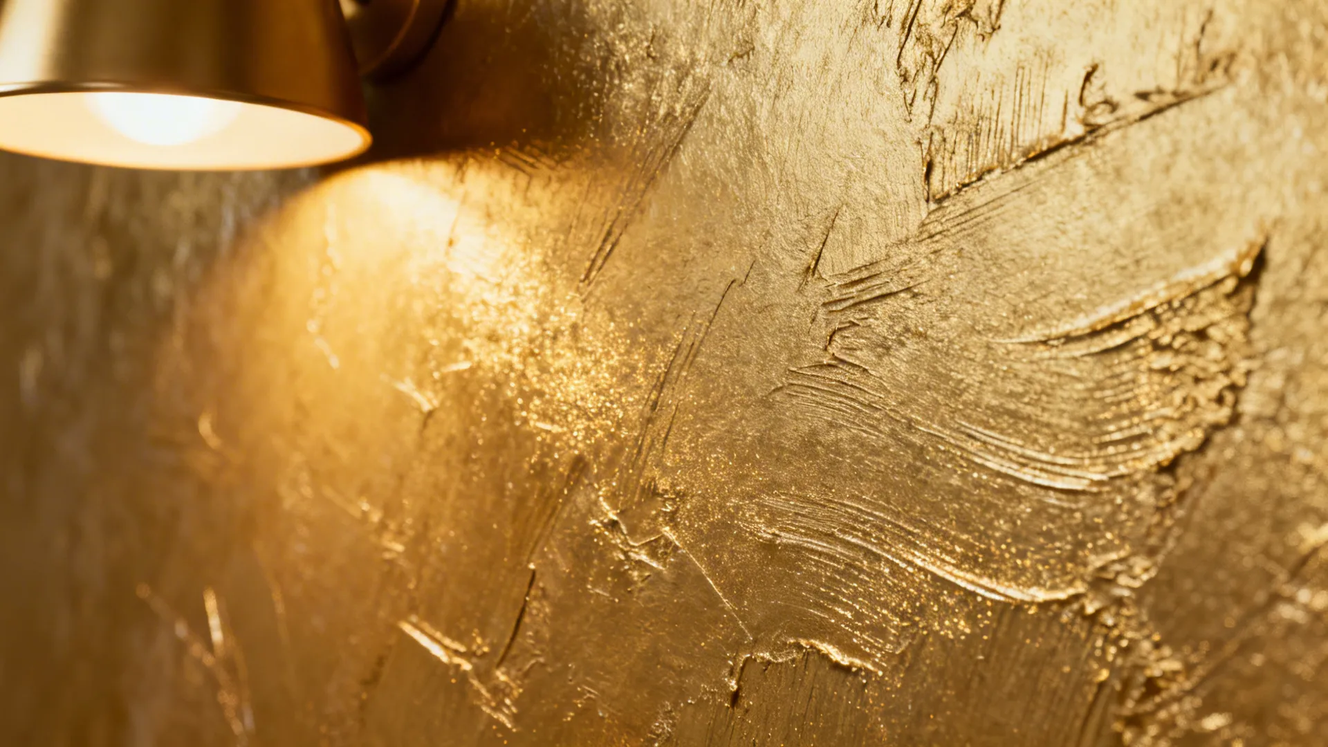 Macro of champagne metallic plaster showing subtle trowel strokes and gentle shimmer.