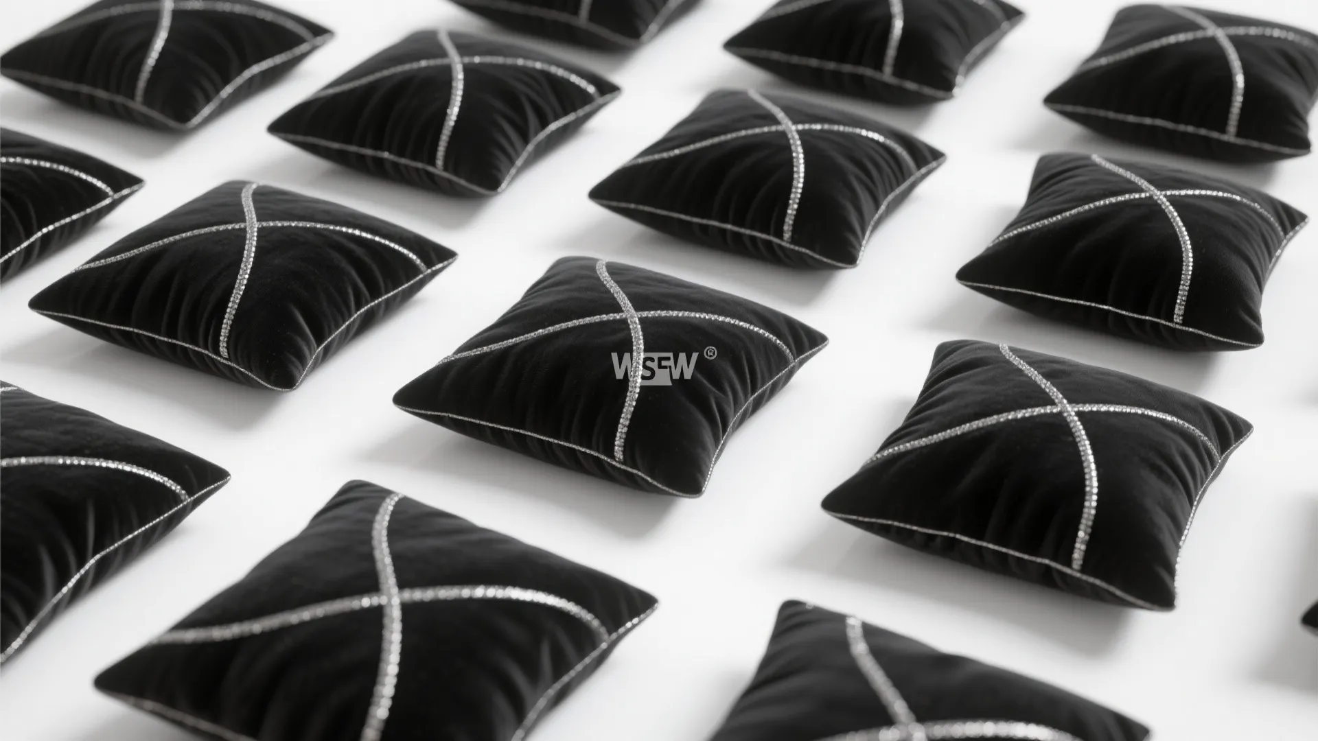 Multiple black square cushions with silver cross patterns arranged in rows on a white background