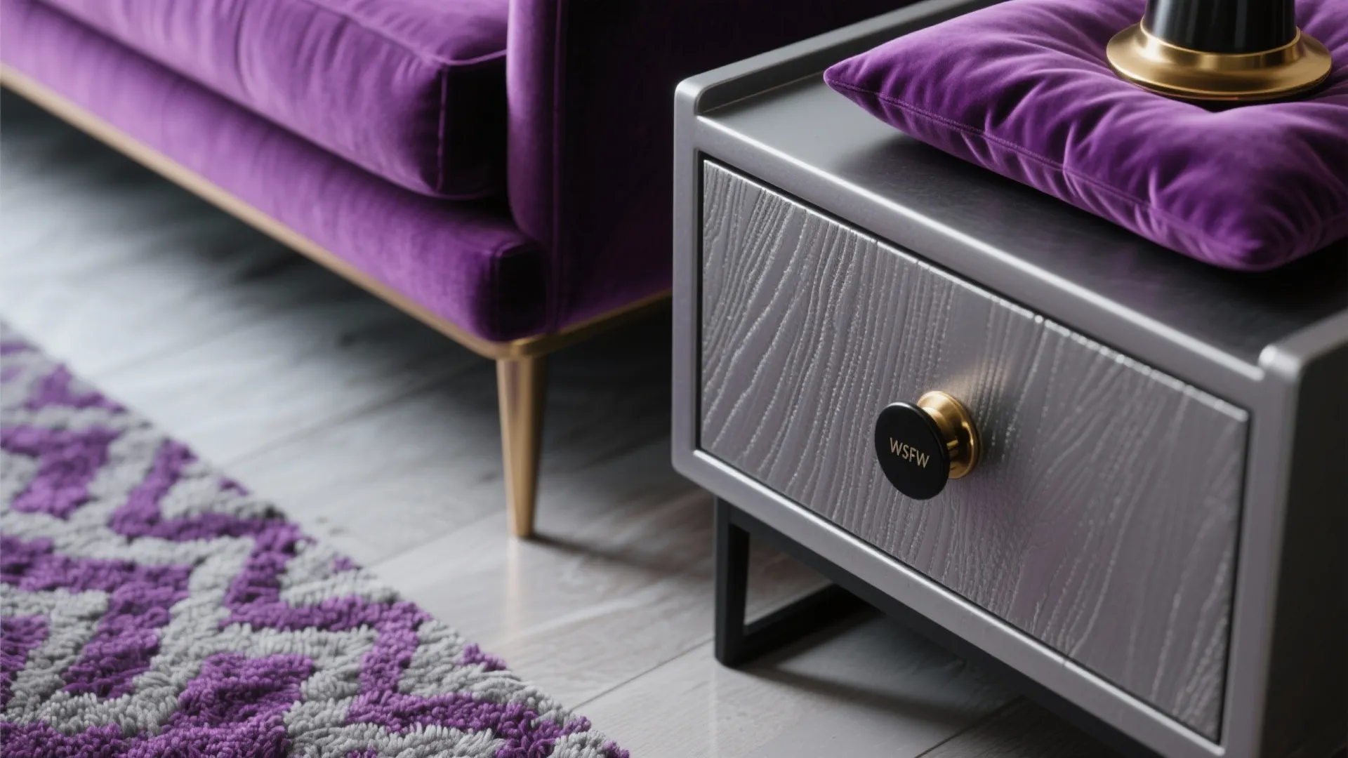 Close up of grey cabinet with gold handle purple sofa purple rug and purple pillow