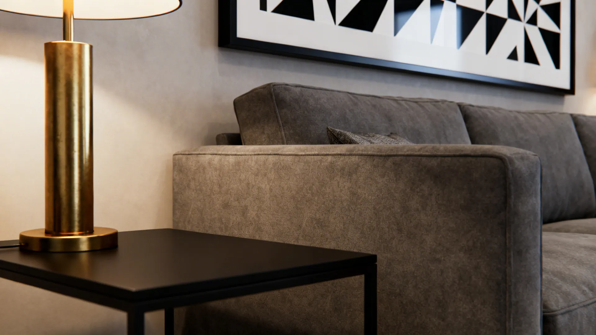 Grey sofa next to black side table with gold lamp and black and white wall art