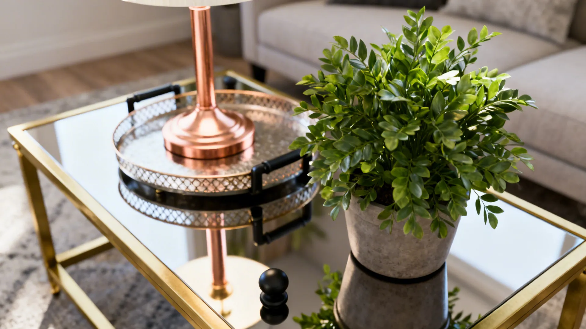 Brass accents and a potted plant on a coffee table providing contrast in a grey-pink scheme