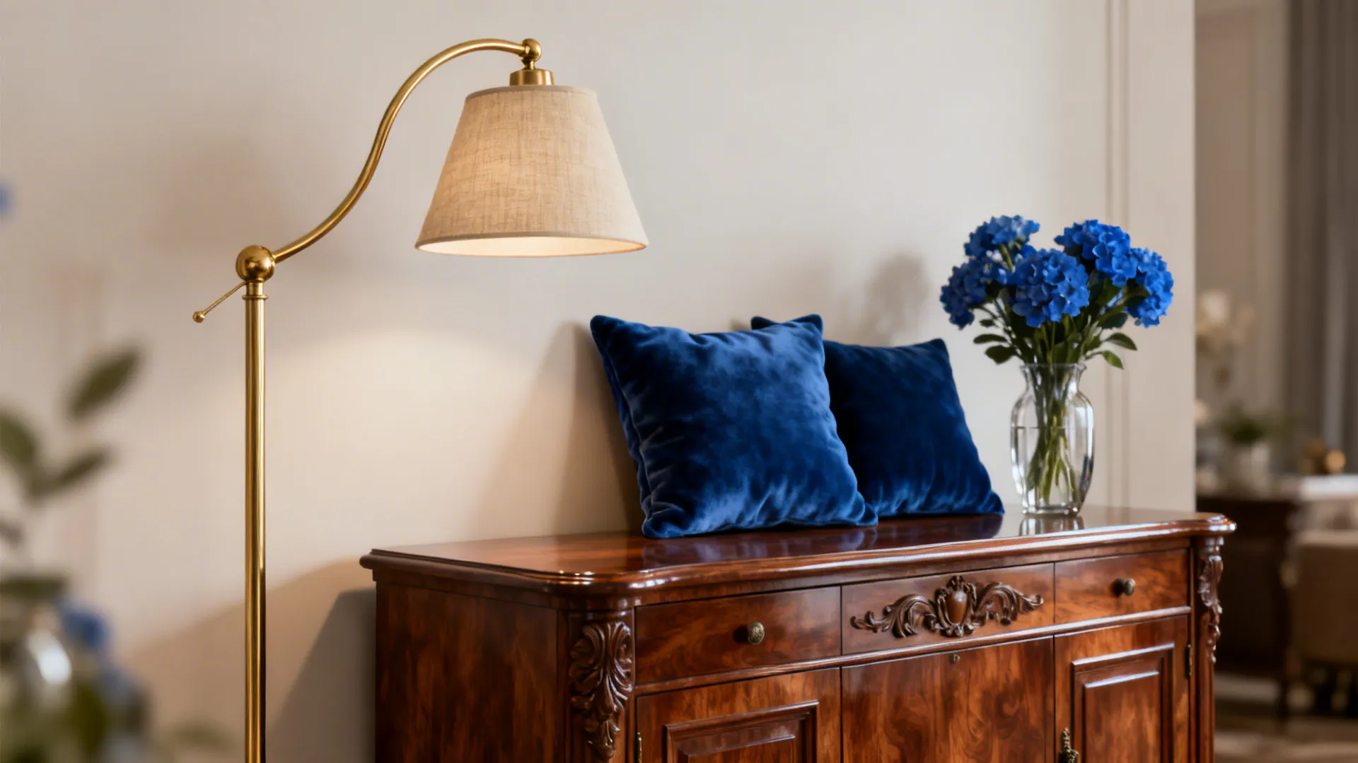 Wooden cabinet with blue pillows blue flowers in a glass vase and a gold floor lamp