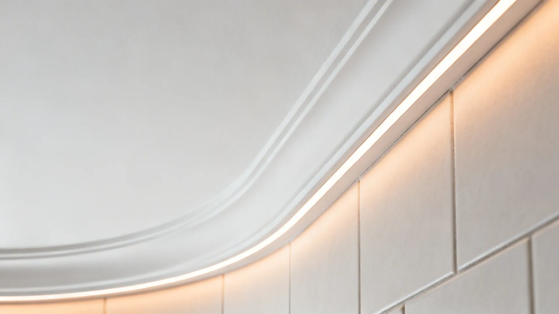 Macro of curved gypsum edge with micro-cove LED creating a soft halo.