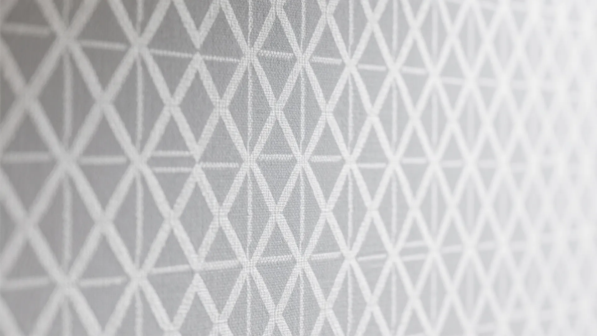 Close up view of grey and white geometric triangle pattern on a textured wall panel surface