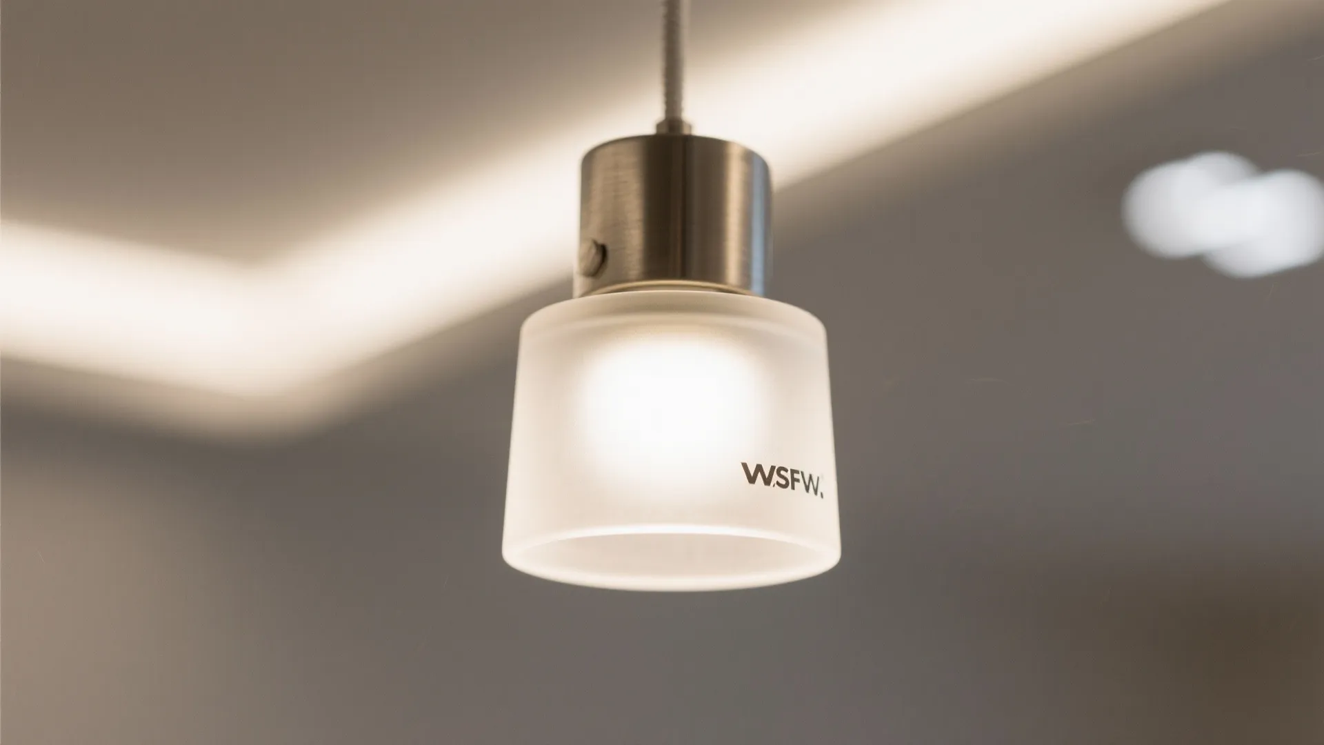 Close up of a frosted glass ceiling light with silver metal base and soft warm glow