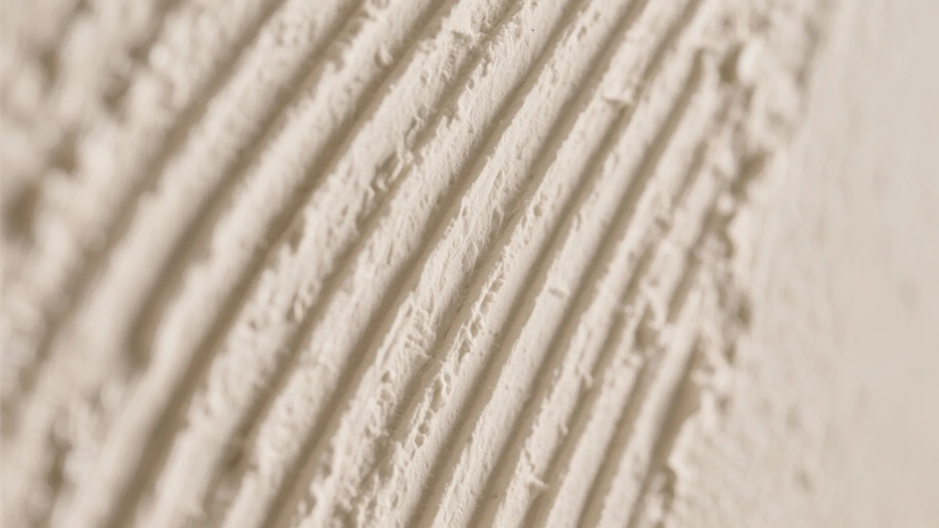 Close up of cream wall plaster showing a rough textured finish with parallel vertical lines