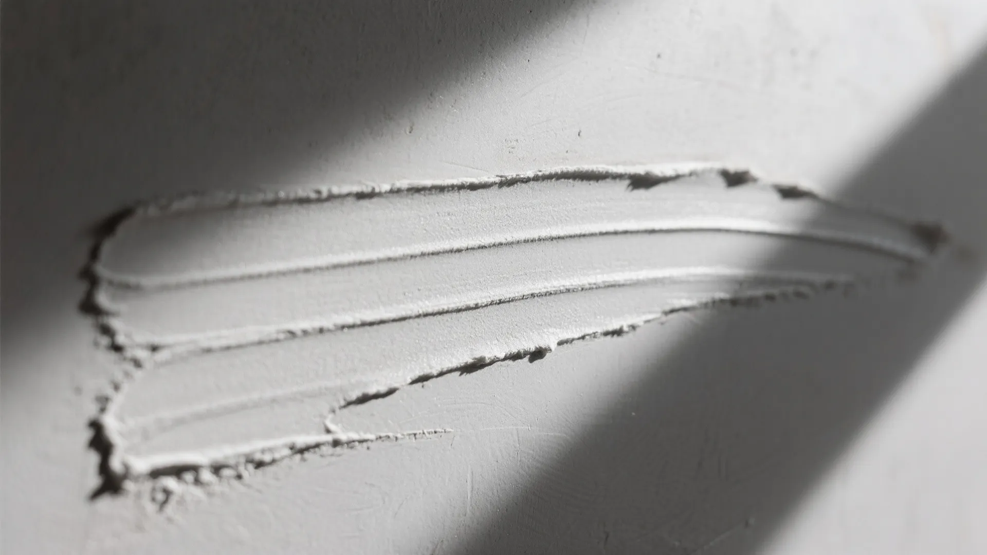 Close up view of grey wall texture showing smooth plaster finish and natural light shadow