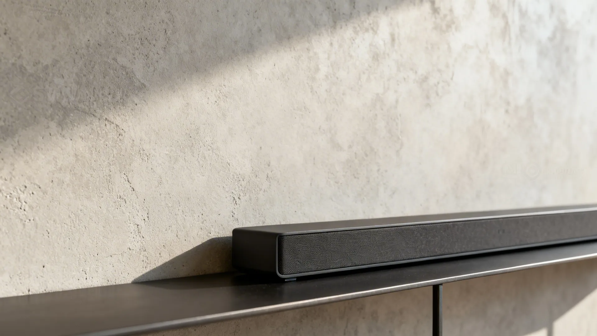Close-up of microcement wall texture with a slim charcoal steel shelf edge and soundbar rail.