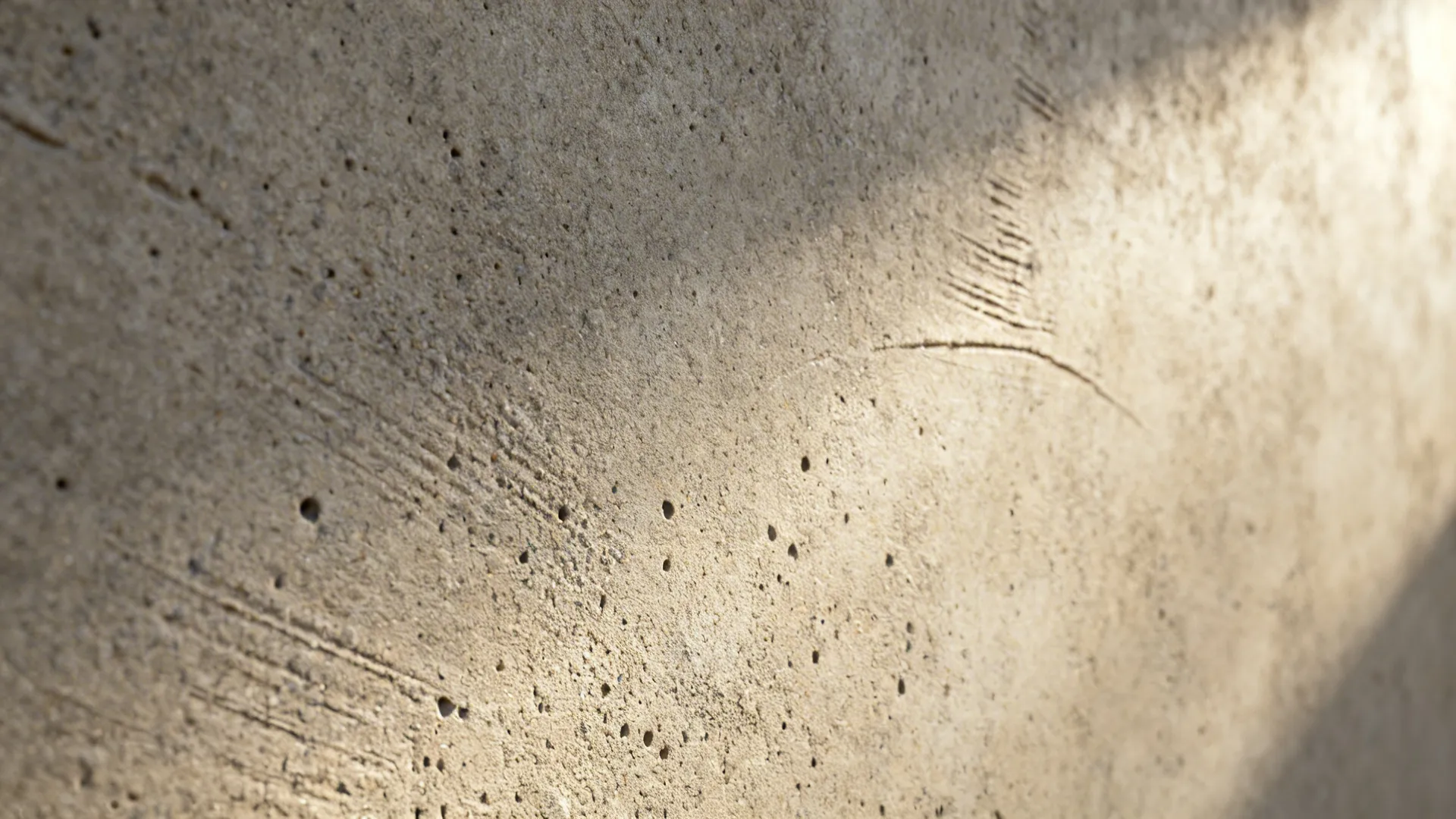 Macro of warm greige micro-concrete wall with fine texture and soft light.