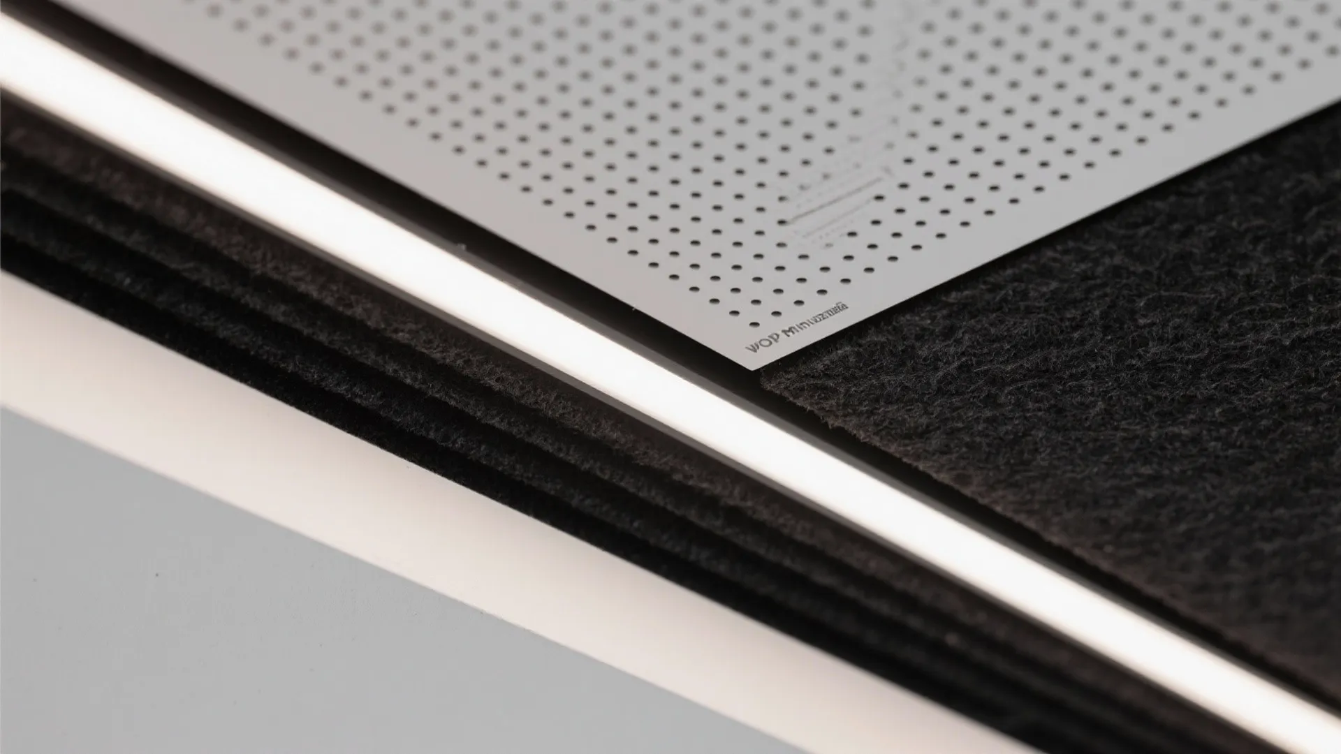Close up view of perforated metal panel with small holes and a bright ceiling light strip