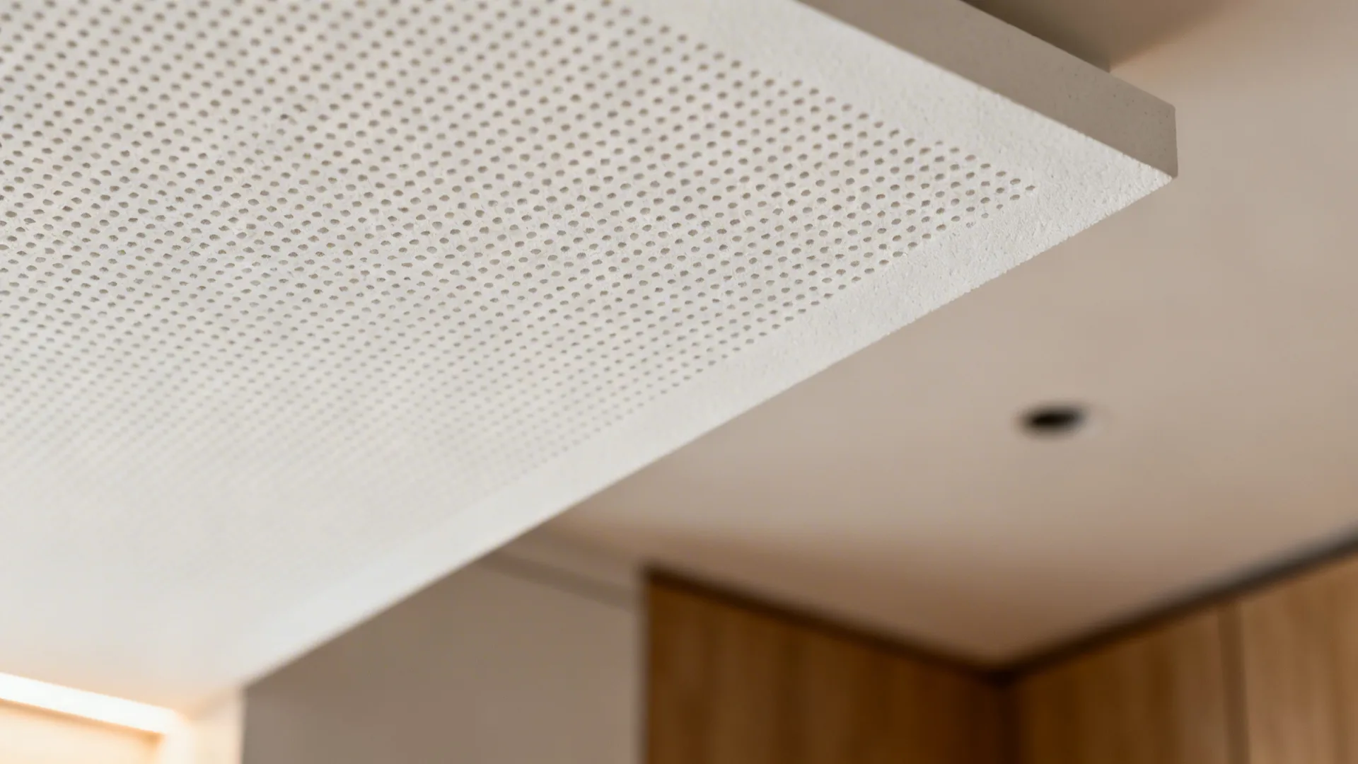 Macro view of micro-perforated acoustic plaster texture with smooth white finish.