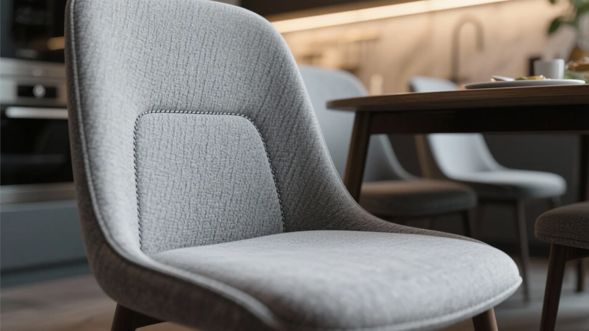 Close up view of a grey fabric chair in a modern kitchen with dining table