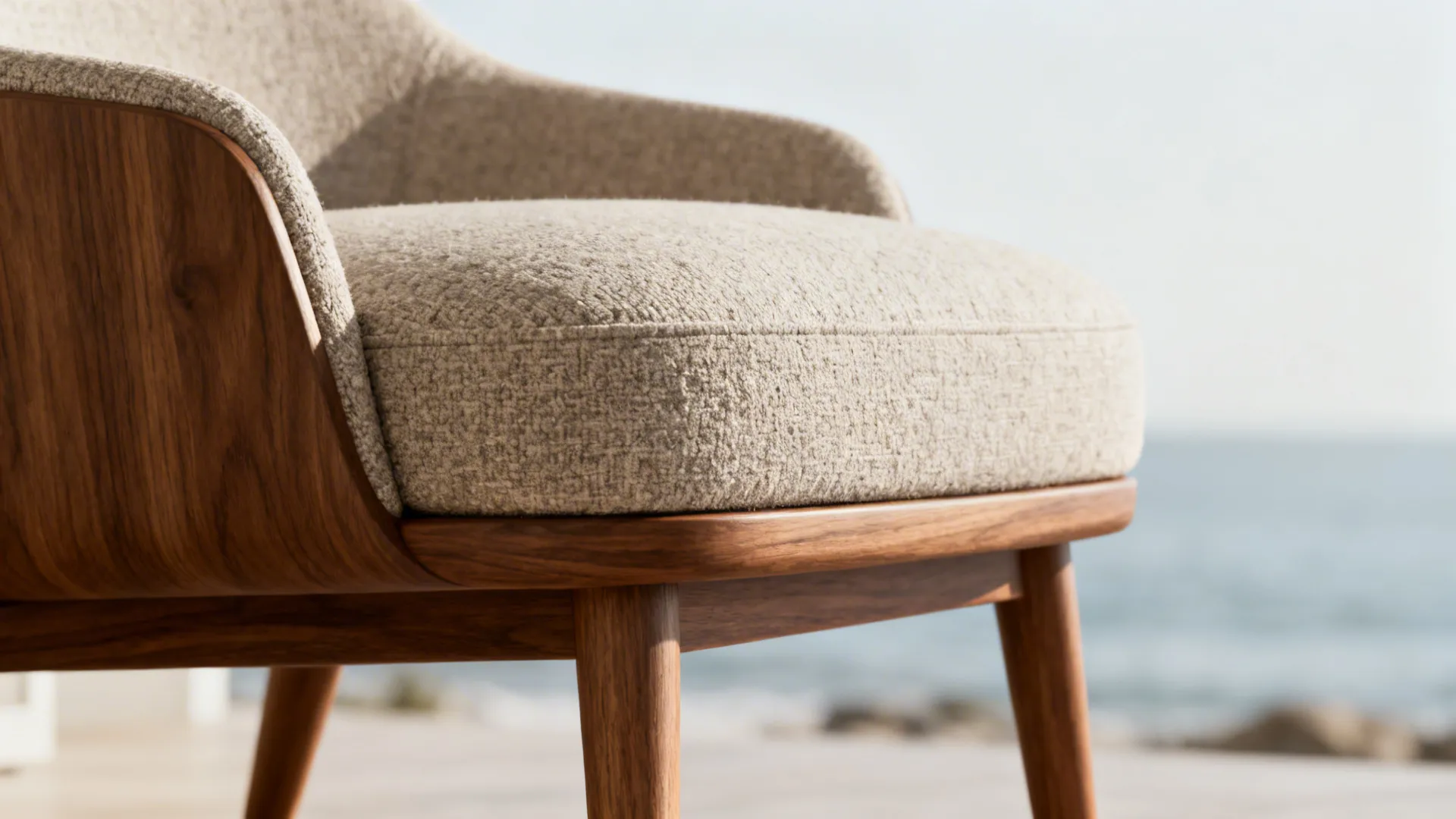 Close-up of a low-profile mid-century slipper chair with wooden legs and neutral cushion.