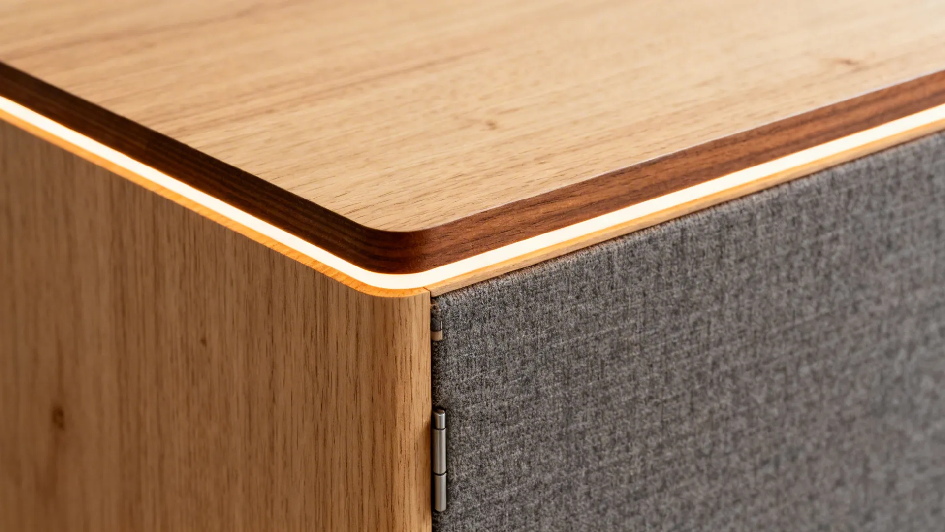 Close-up of veneered plywood with solid-wood edging, fabric-backed panel seam, and a touch-latch detail.