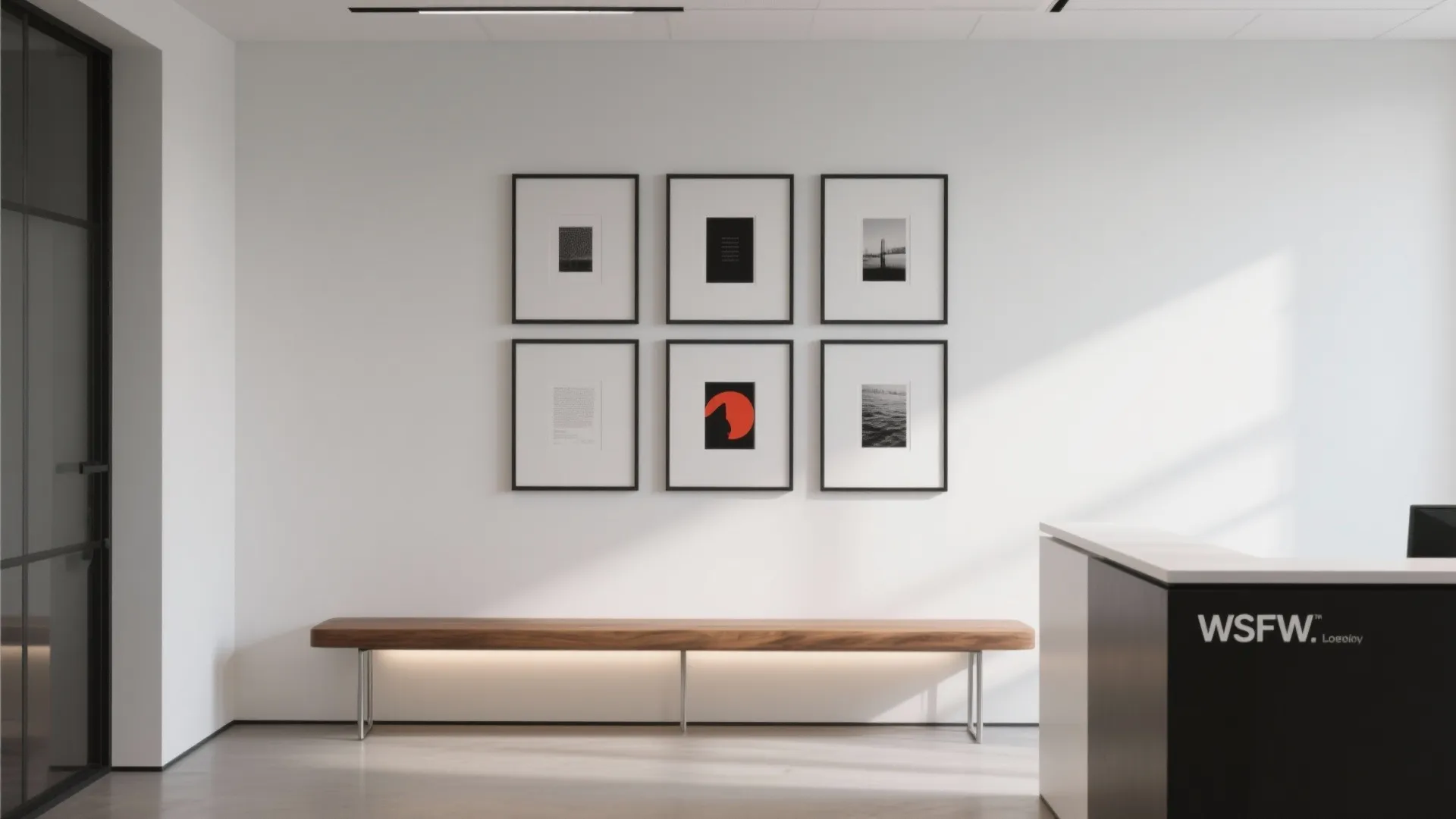 Modern office waiting area with six framed art prints long wooden bench and black reception desk