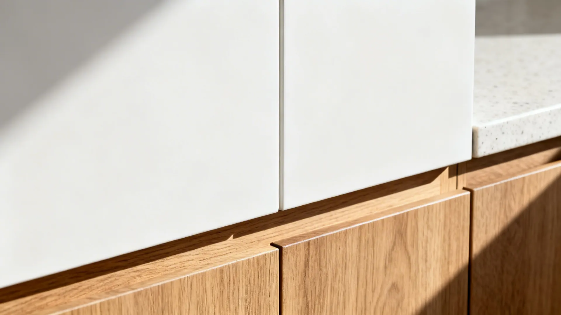 Close up of white kitchen cabinet doors and wooden lower cabinet drawers with natural bright sunlight