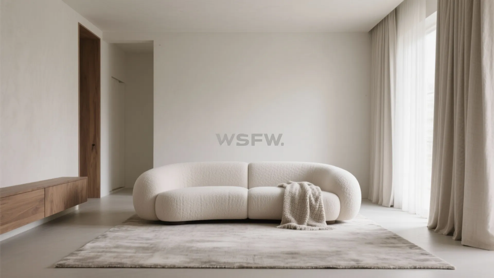 Minimalist living room featuring a curved white sofa on a large rug with sheer curtains