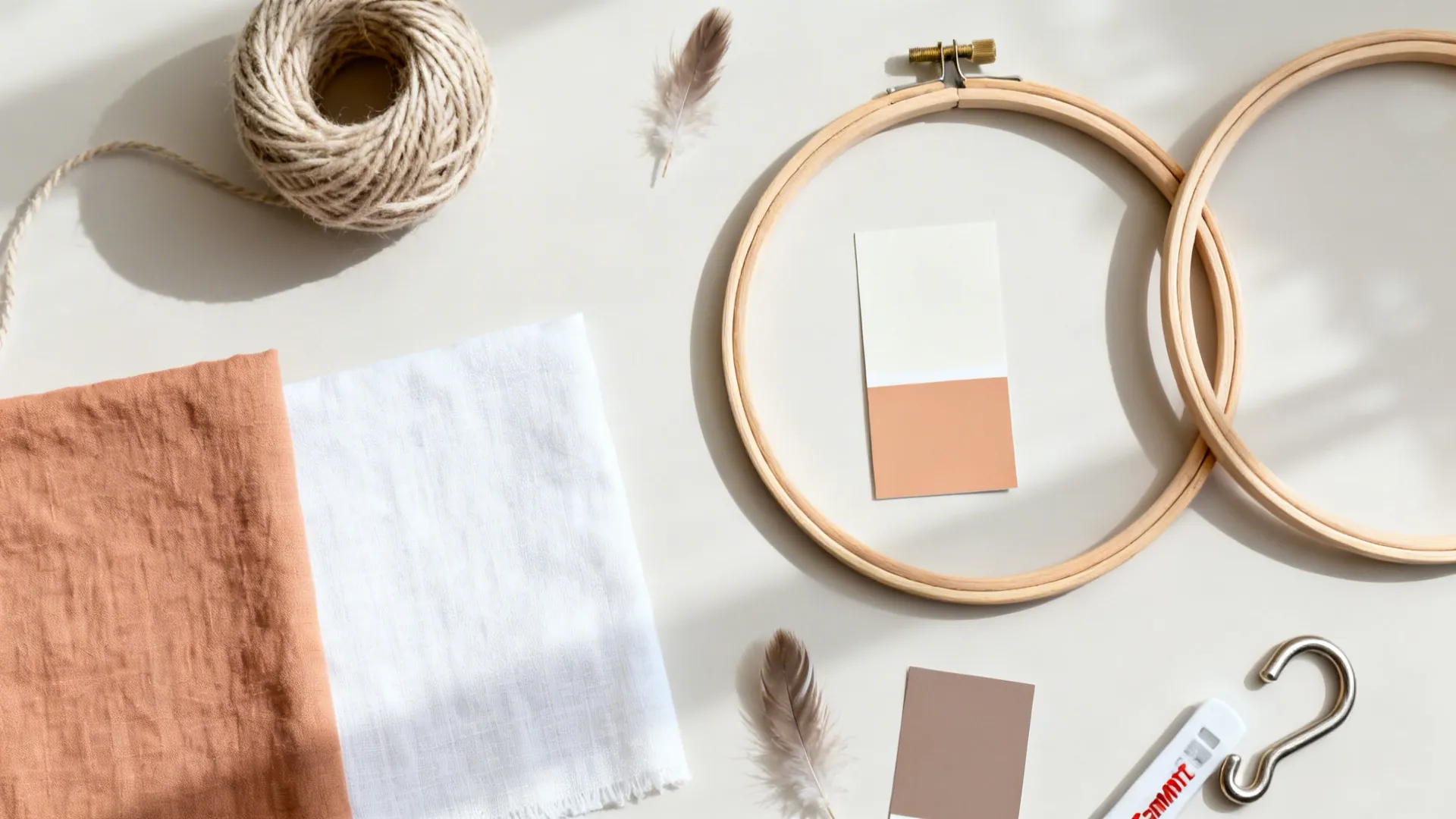 Top-down neutral flat lay of cotton cords, wooden hoops, linen swatches, paint chips, and hooks.