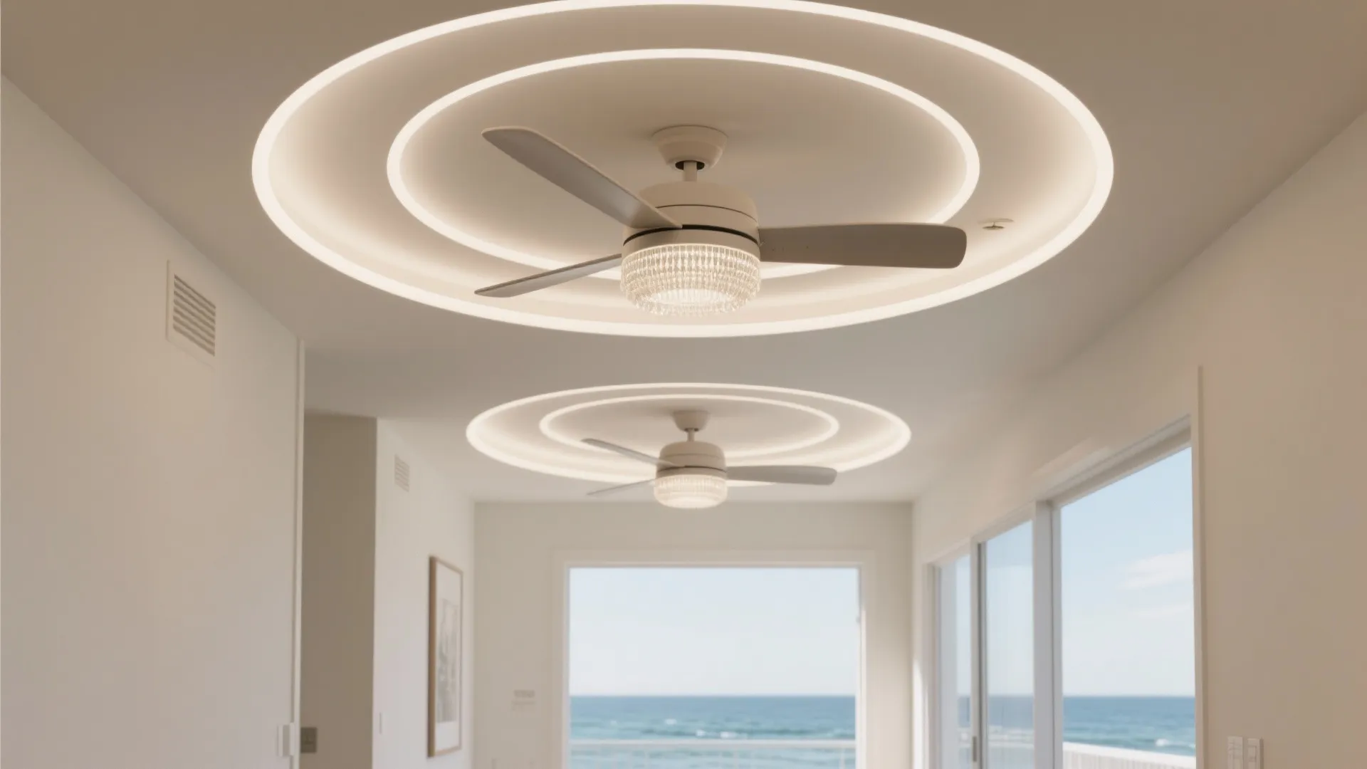 Modern white ceiling fan with round light rings installed in a bright room with ocean views