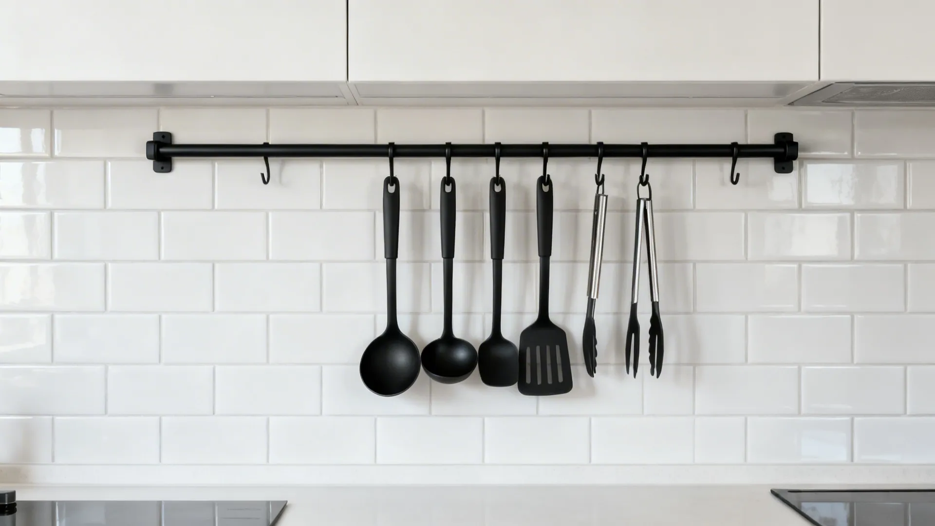 Matte black rail-and-hook utensil rack on white tile with tools neatly aligned.
